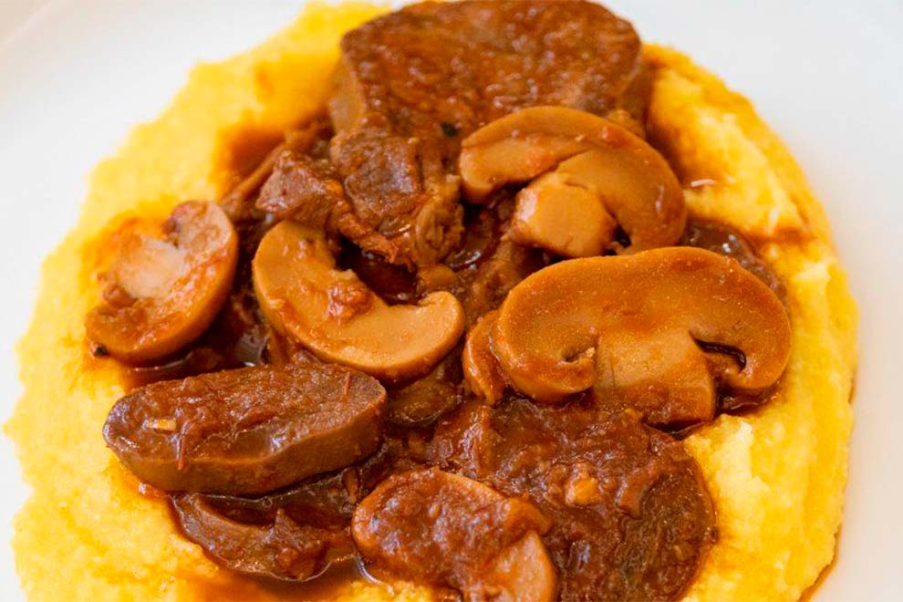 Prato de polenta com carne e cogumelos.