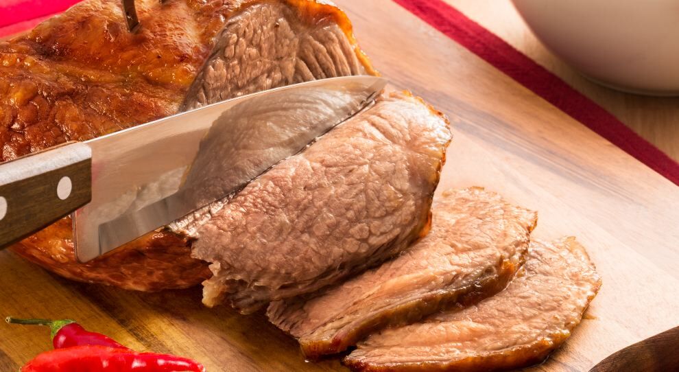 Carne assada suculenta sendo fatiada na tábua