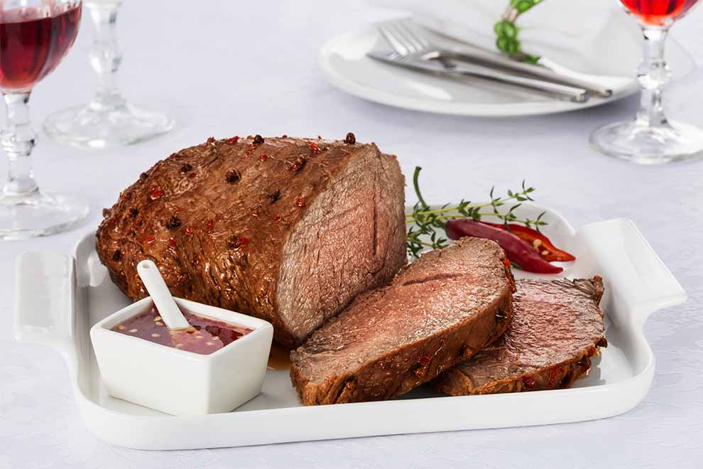 Prato com carne assada e molho ao fundo.