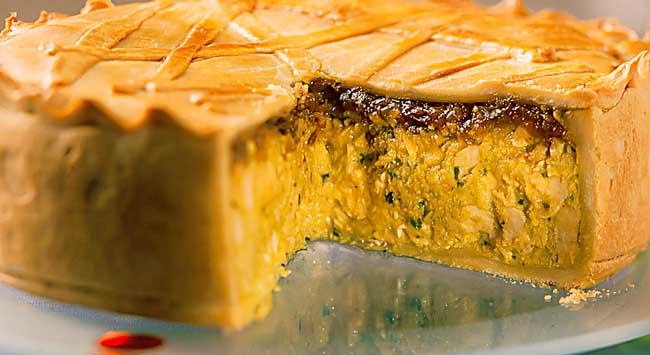 Torta de frango e curry em uma travessa transparente.