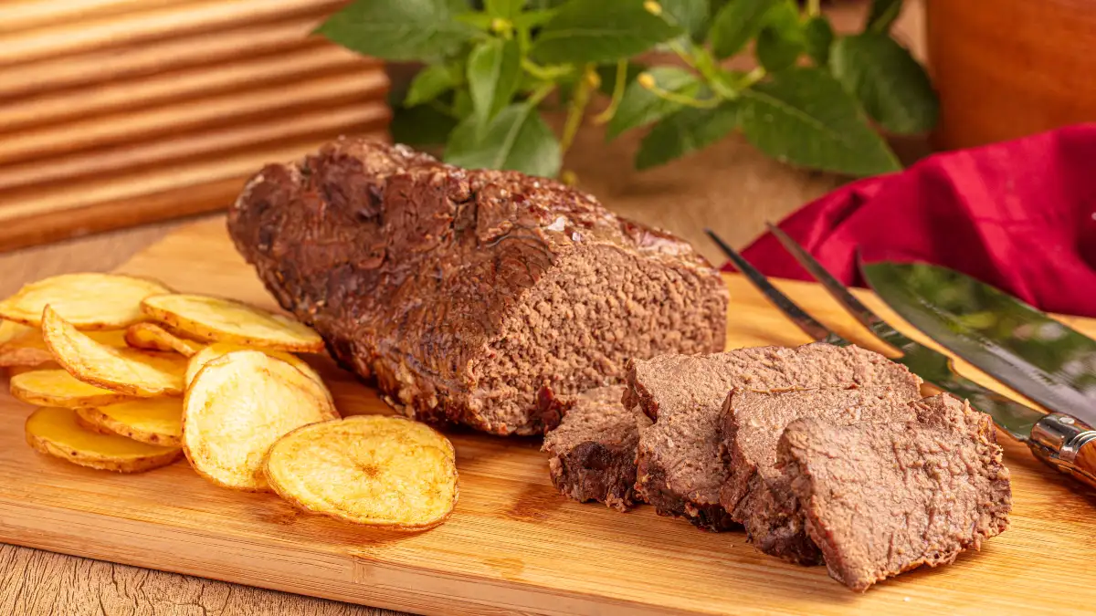 Tábua de madeira servindo com base para um pedaço de alcatra com manteiga de alho, servidas com batatas.
