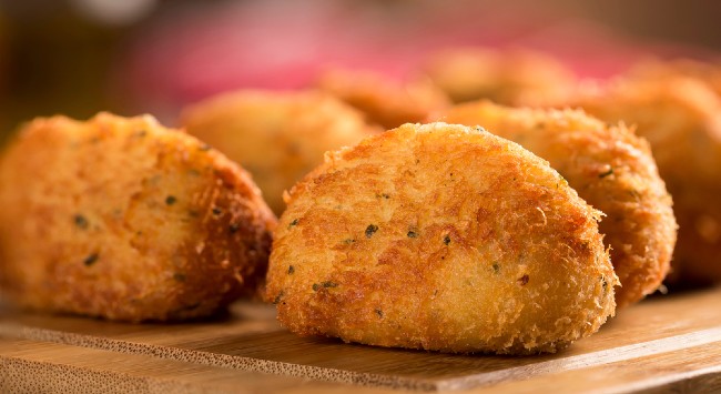 Uma porção de bolinho de bacalhau com batata na tábua de madeira.