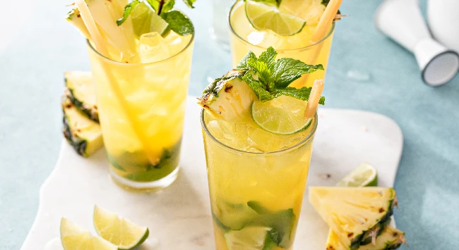 Caipirinha de abacaxi com hortelã em um copo alto.