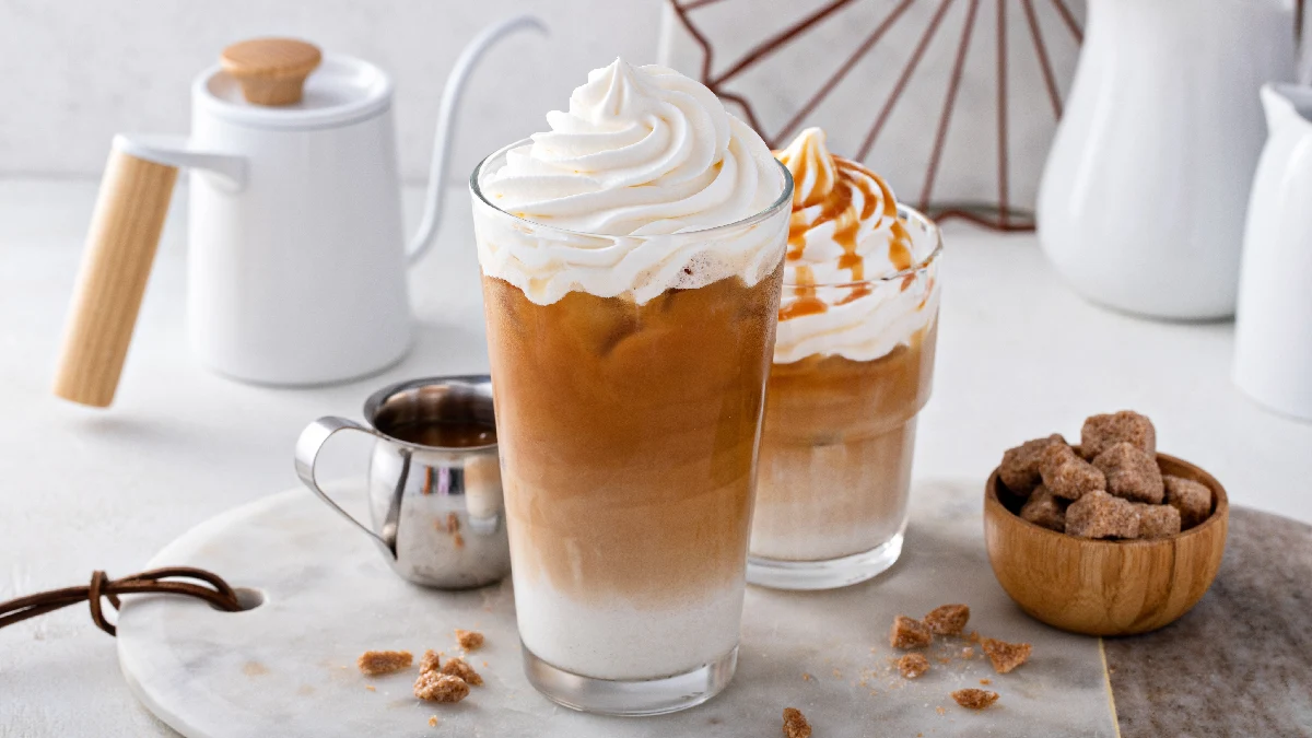 Cappuccino gelado servido em um copo alto com chantilly em cima.