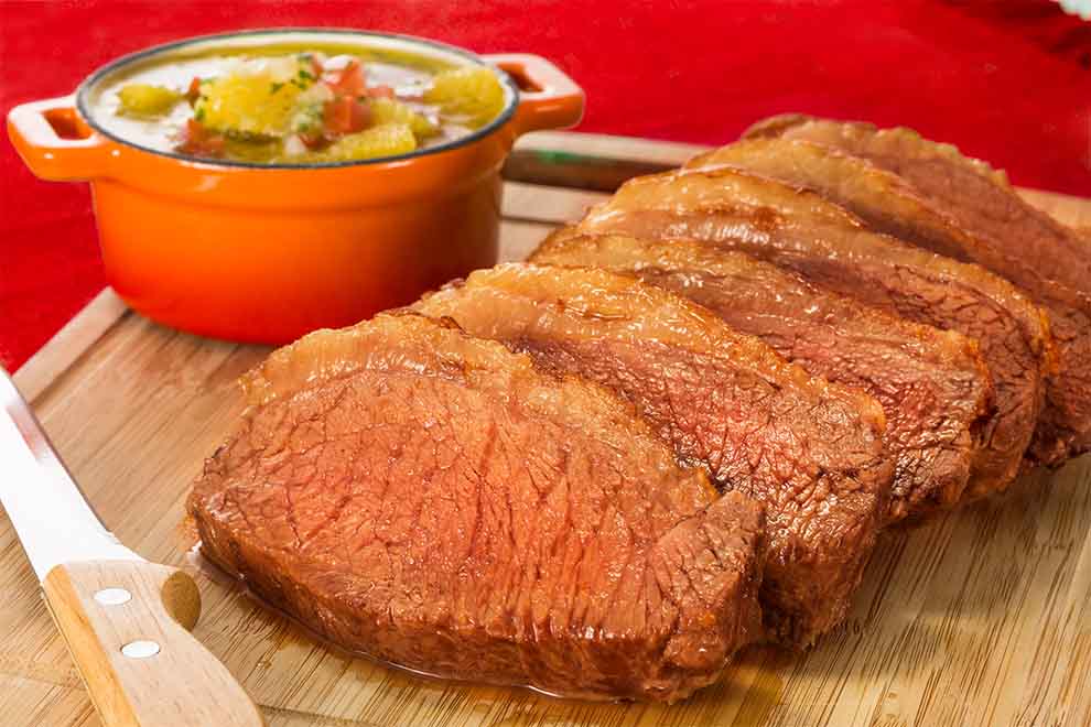 Carne assada fatiada com molho ao fundo