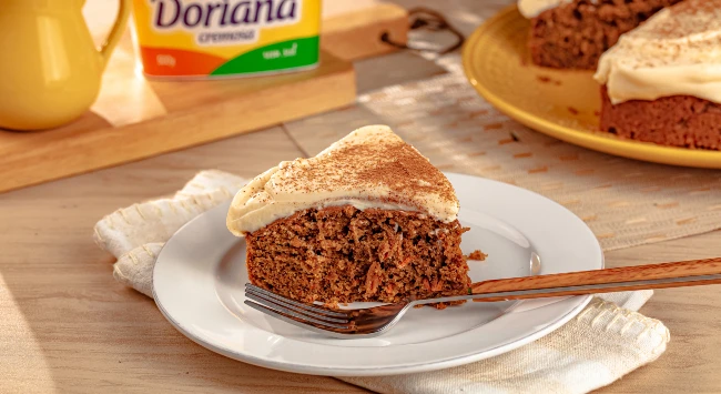 Fatia de carrot cake servida em um prato de sobremesa branco.