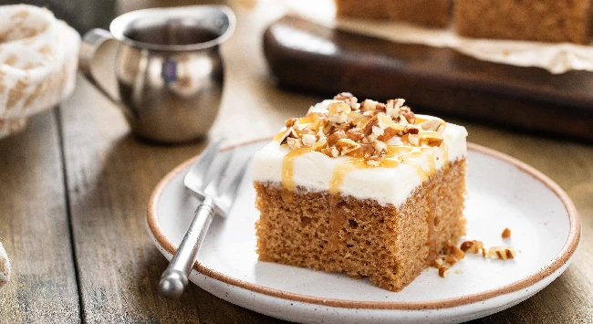 Bolo de cenoura inglês servido com cobertura de cream cheese em um prato de sobremesa.