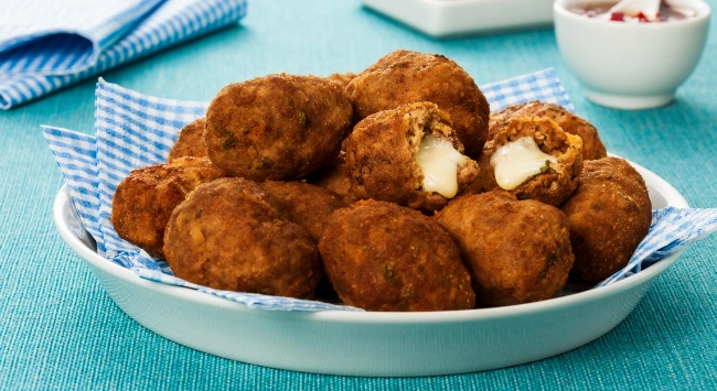 Croquete de carne moída recheado com queijo, servidos em um uma travessa de porcelana branca.