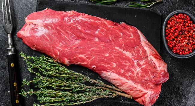 Uma tábua simples com pedaço cru da carne fraldinha.