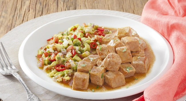 Cubos de lombo suíno ao molho madeira com vinagrete picante de abacate em um prato branco.