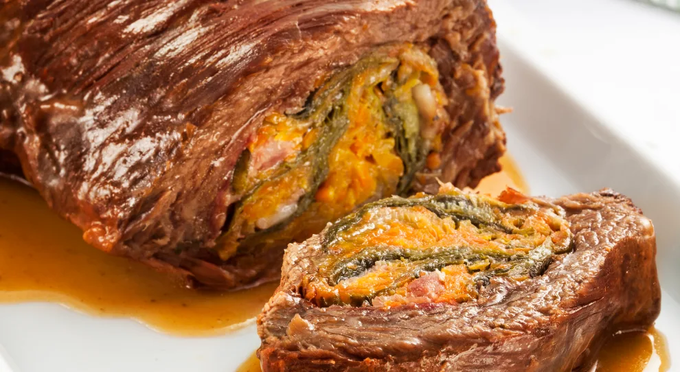 Peça de carne maminha com recheio e uma fatia ao lado.