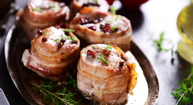 Medalhões de frango enrolados com bacon em uma travessa.