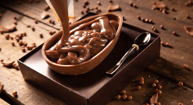 Ovo de Páscoa caseiro sendo recheado com brigadeiro cremoso de chocolate.