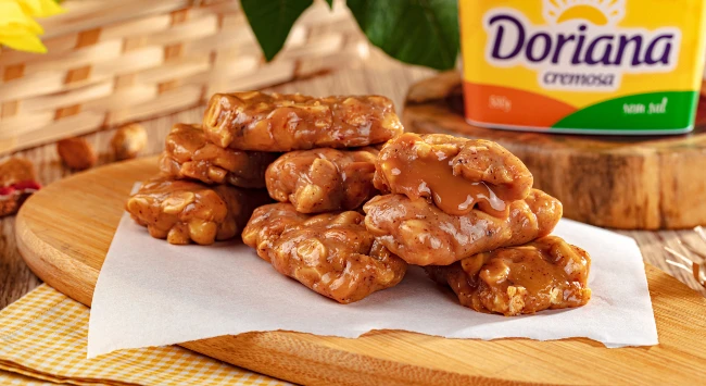 Pé de moça recehado com doce de leite, disposto em uma tábua de madeira.