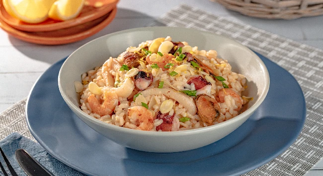 Risoto de frutos do mar servido em um prato fundo branco.