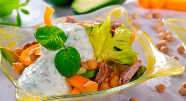 Salada de verão feita com Peito de Frango Defumado Seara e coberto com molho de iogurte com maionese, servido em uma travessa branca com bordas amarelas.