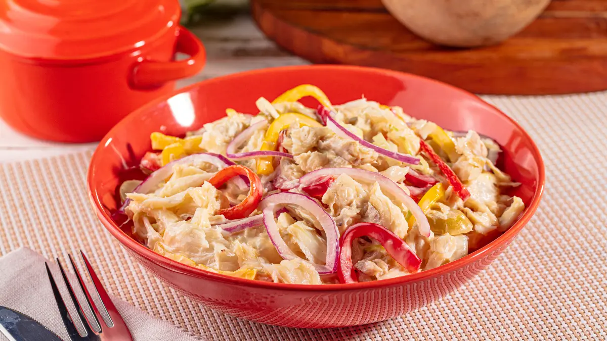 Salpicão de bacalhau servido em uma tigela vermelha grande e funda.