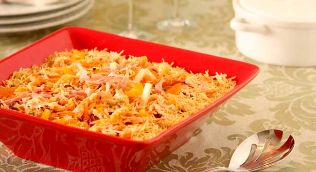 Salpicão festivo de frango defumado com batata palha e maçã em uma travessa vermelha.