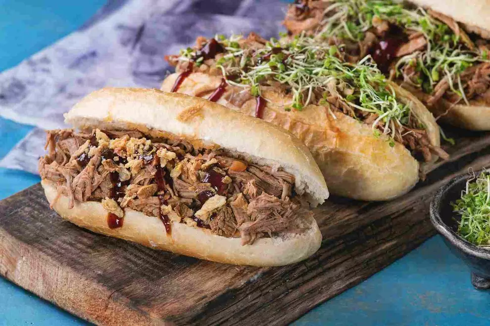 três sanduíches encima de uma tábua de madeira