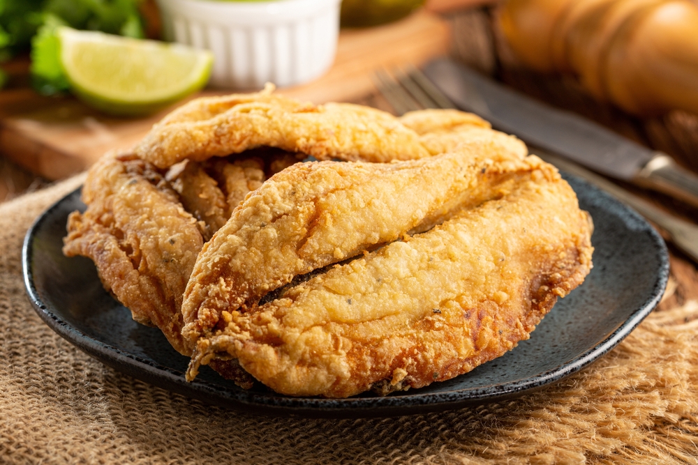 sardinha frita empanada servida em um prato preto redondo