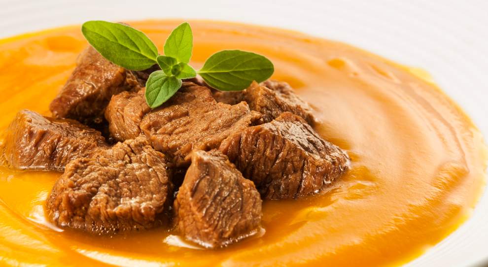 Sopa de abóbora com Acém Friboi em cubos, servido em um prato branco.