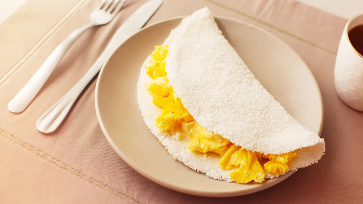 Tapioca com ovo servida em um prato bege.